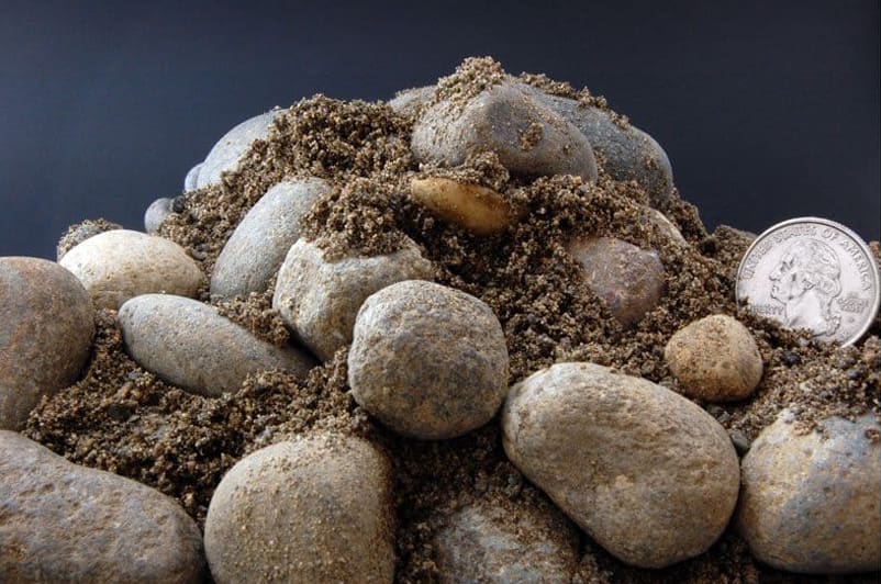 A quarter sits on top of a pile of Foundation Material Class A, providing a size comparison.