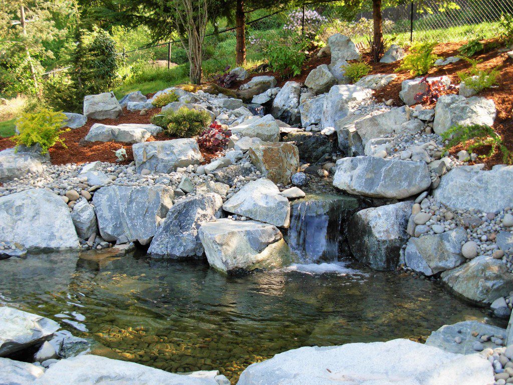 waterfall build from basalt rock empties into pond