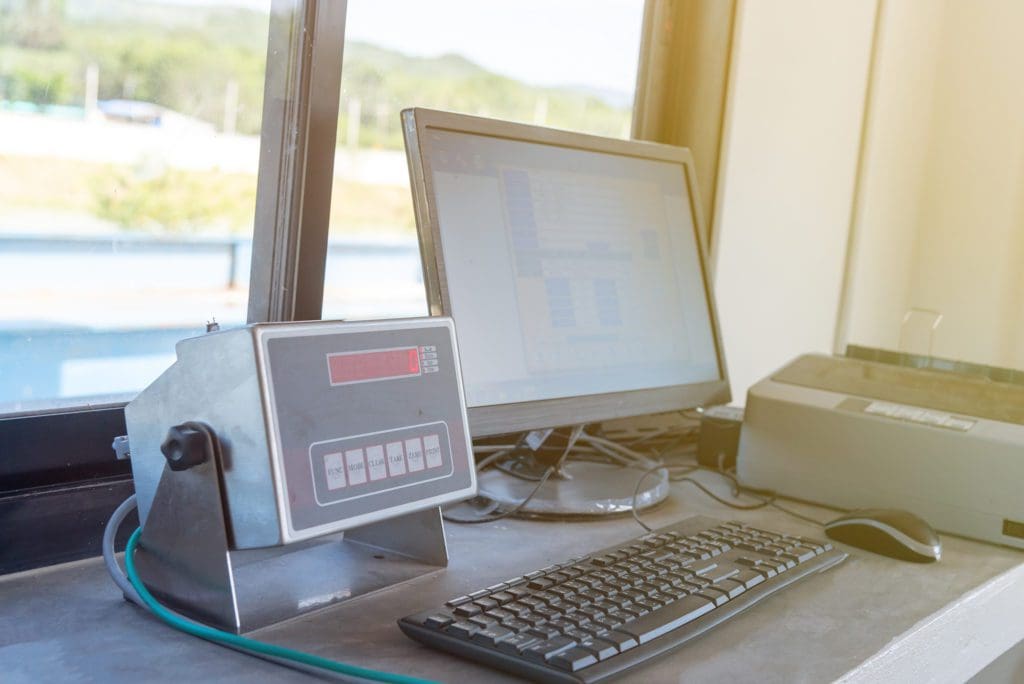 Computer next to a window. A monitor is next to the computer and shows the vehicle's weight.