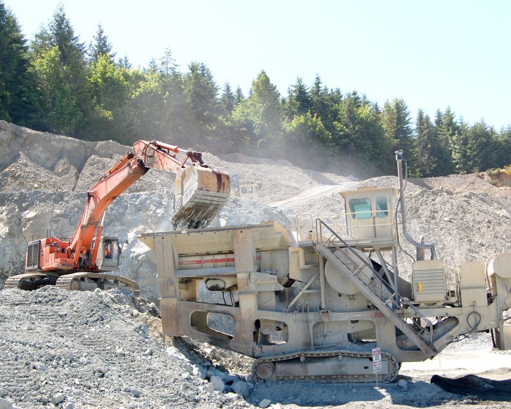 An excavator deposit material into a jaw crusher, which looks kind of like a sandcrawler from Star Wars.