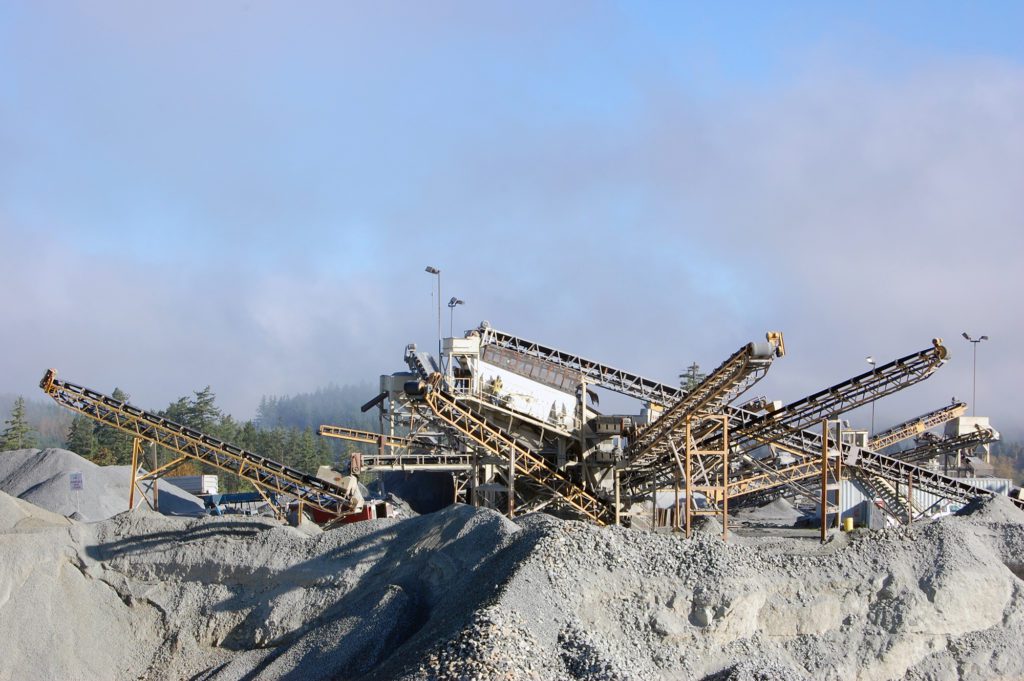 A series of conveyor belts and machines are seen sitting on a rocky ridge. 