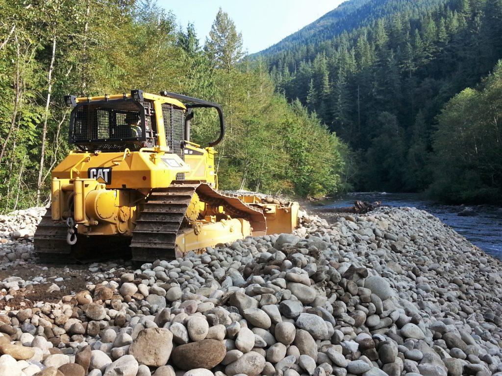 a dozer pushes river rock during a streambed restoration project