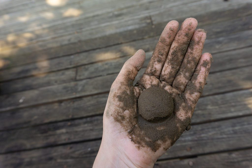a hand with a ball of wet, molded ultrafine sand