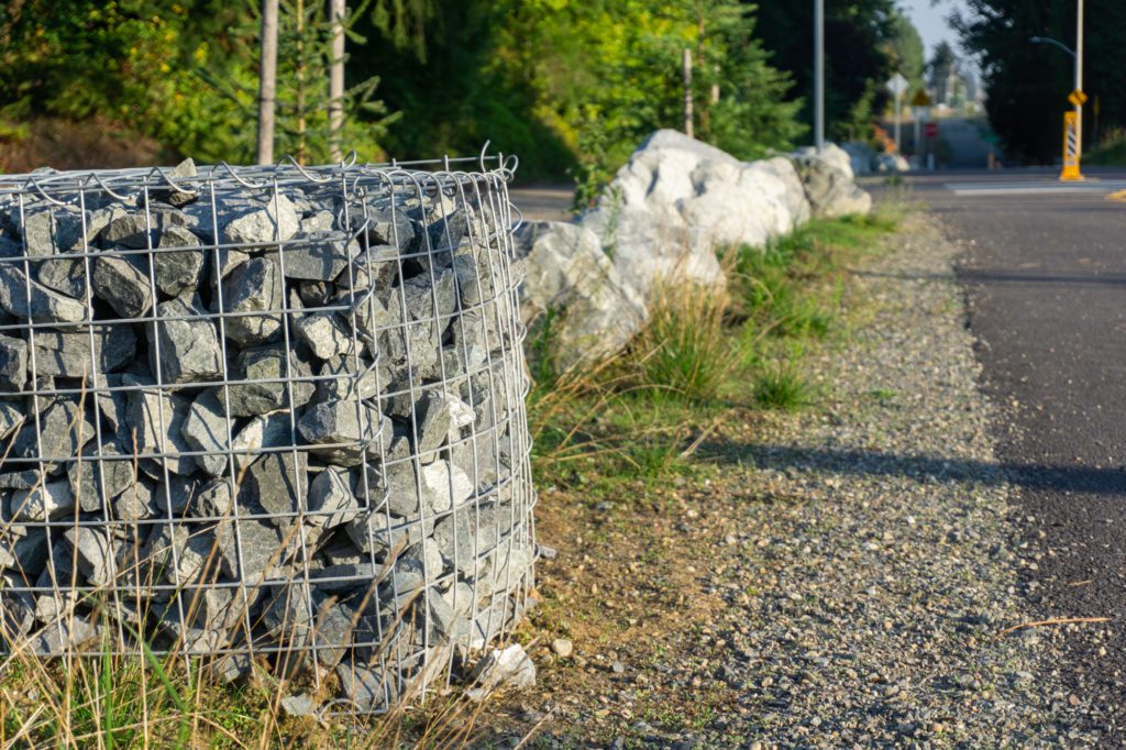 gabion basket filled with rocks next to paved trail