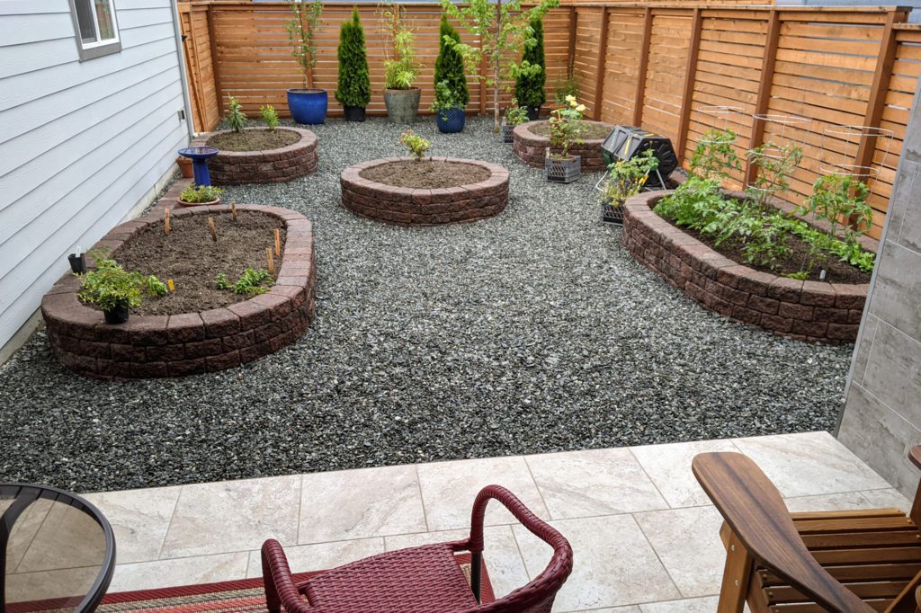 gravel surrounding 5 garden beds made from pavers