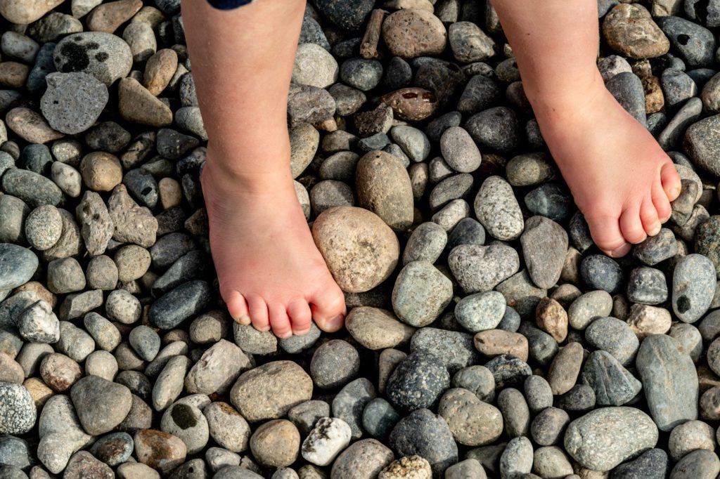 child's feet on a variety of colorful round rocks