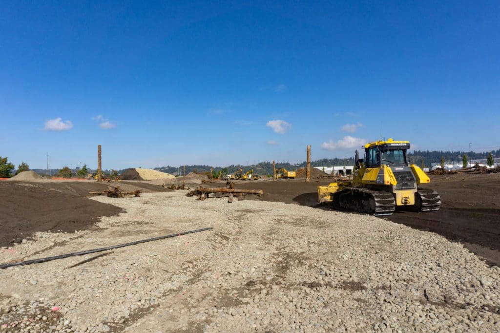 a dozer next to a dry creek bed made up of round river rock