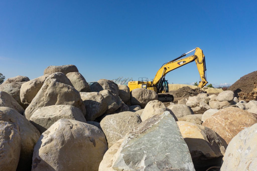 pile of large round boulders in front of an excavator