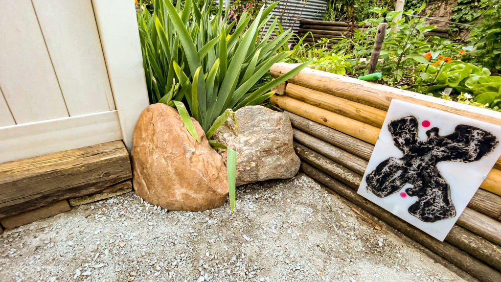 reclaimed boulders add a decorative touch next to a garden bed decorated with a piece of art