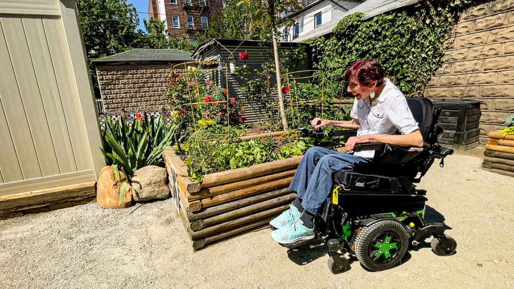 woman in a motorized wheelchair admires a raised garden bed