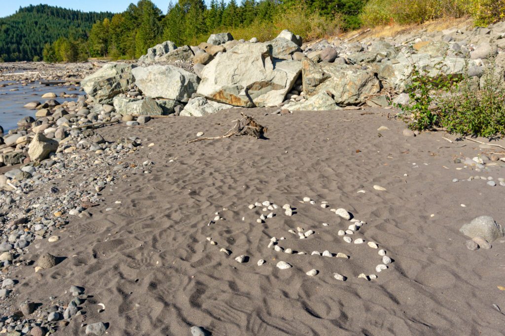 granite rocks in a heart shape in sand with levee rock in the background