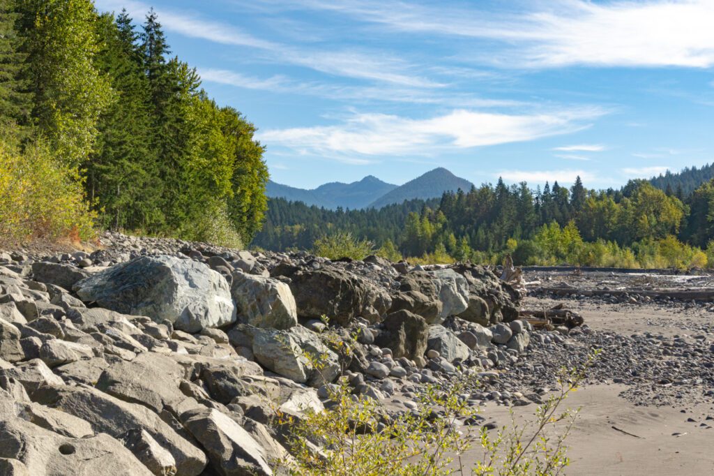 levee rocks with forested mountains in the background