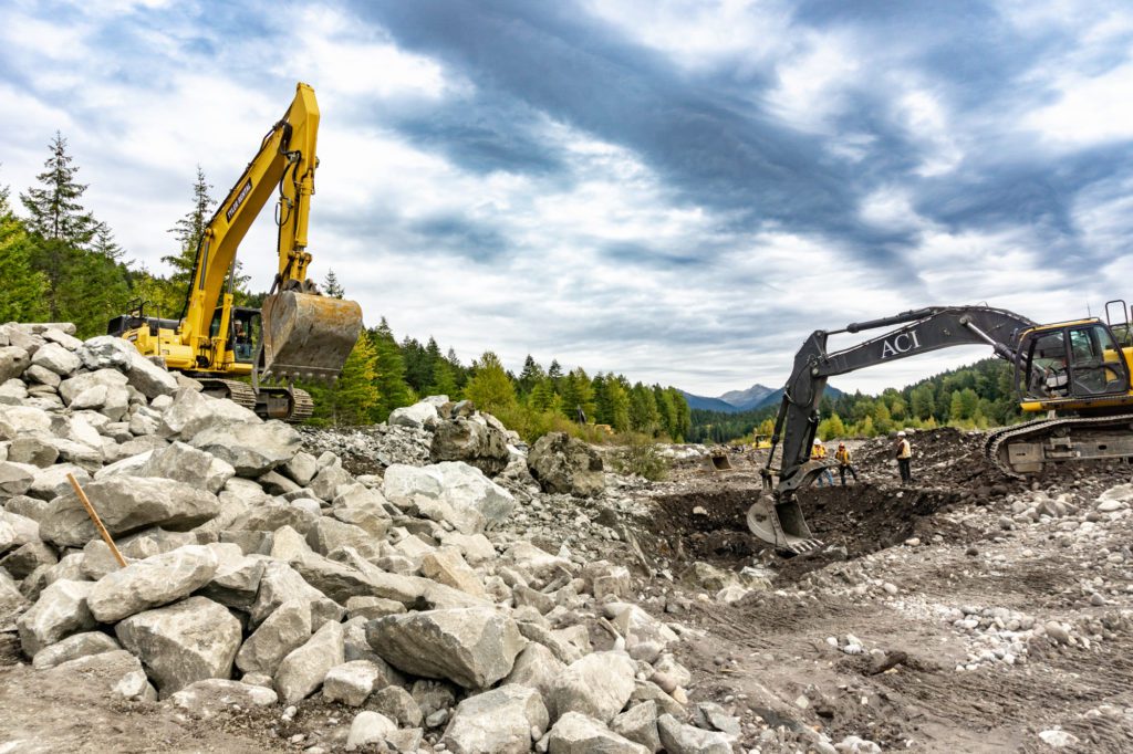 excavators moving boulders next to the Nisqually River levee