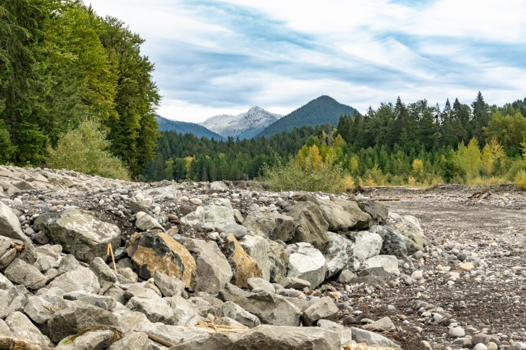 a deflector made of rock along the Nisqually River levee with mountains in the distance
