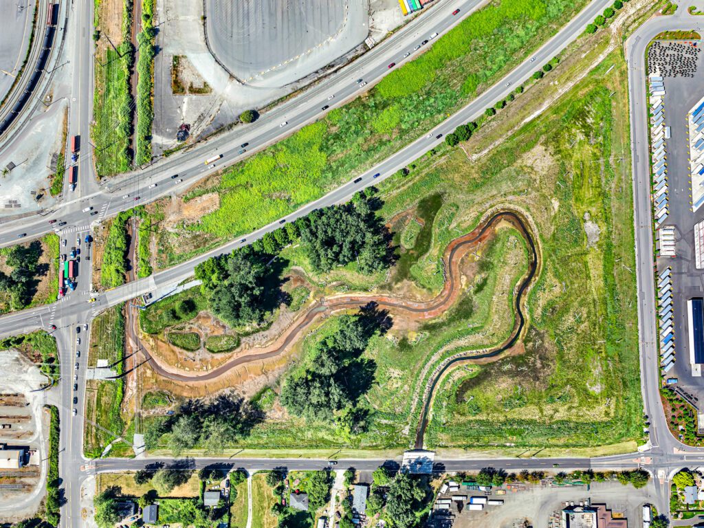 An aerial view shows Highway 509 and local roads juxtaposed with the creek meandering through the wetland.