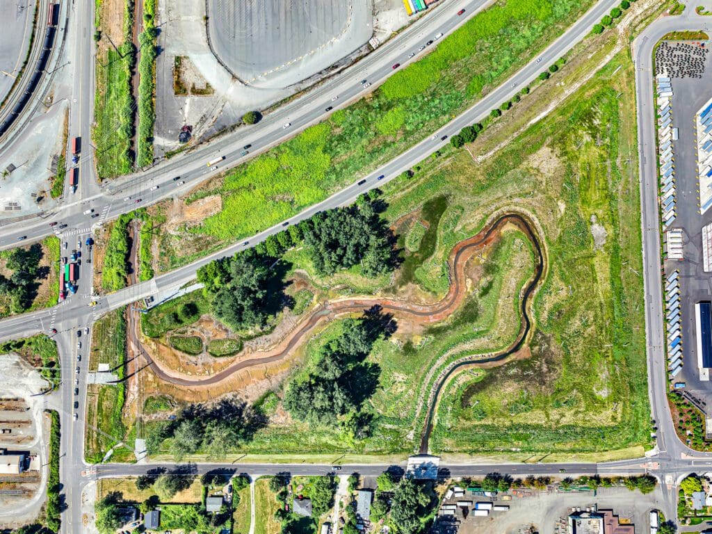 An aerial view shows Highway 509 and local roads juxtaposed with the creek meandering through the wetland.