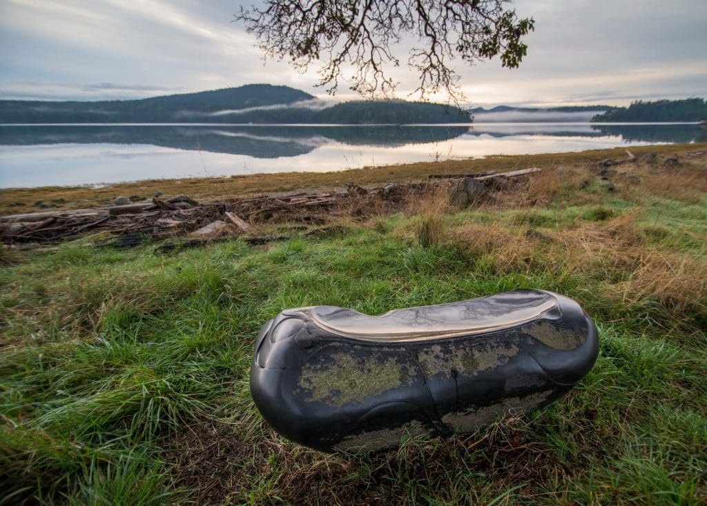 A glossy bench with interesting lines and shapes can be seen in the foreground. A body of water can be seen in the background.