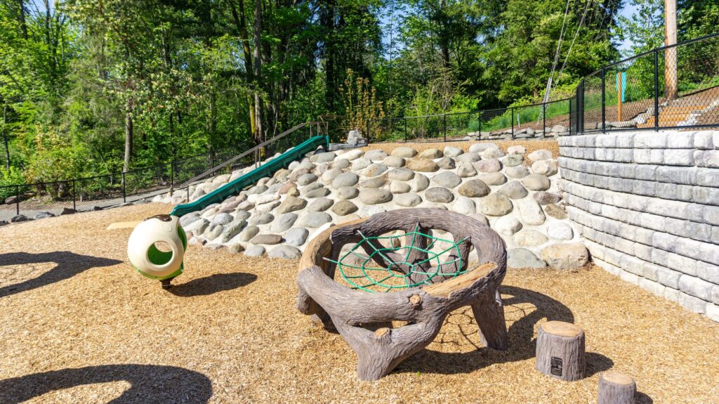 children's playground with a boulder rock wall in the background