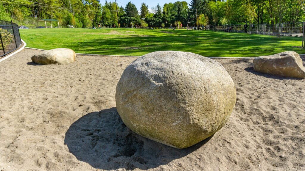 boulder in a sandy area next to a lawn