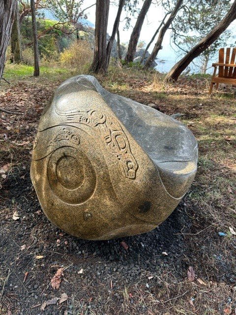 boulder carved into a long granite bench with Native American-inspired carvings