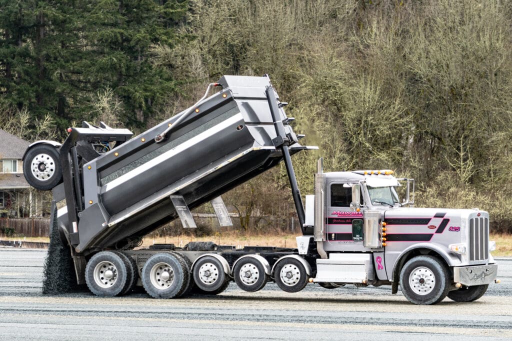 a truck dumps gravel onto a field