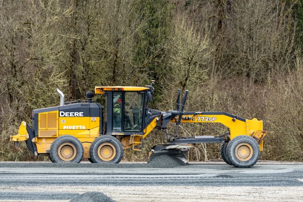 a scraper is seen from a distance grading gravel