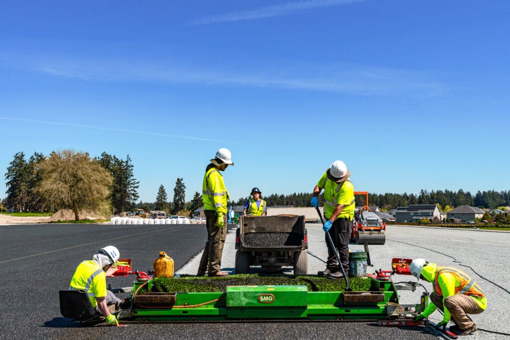 workers smooth out paved E-Layer and load a paving machine with more material