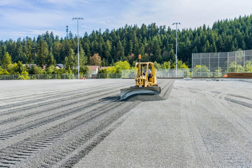A bulldozer grades a field of gravel.