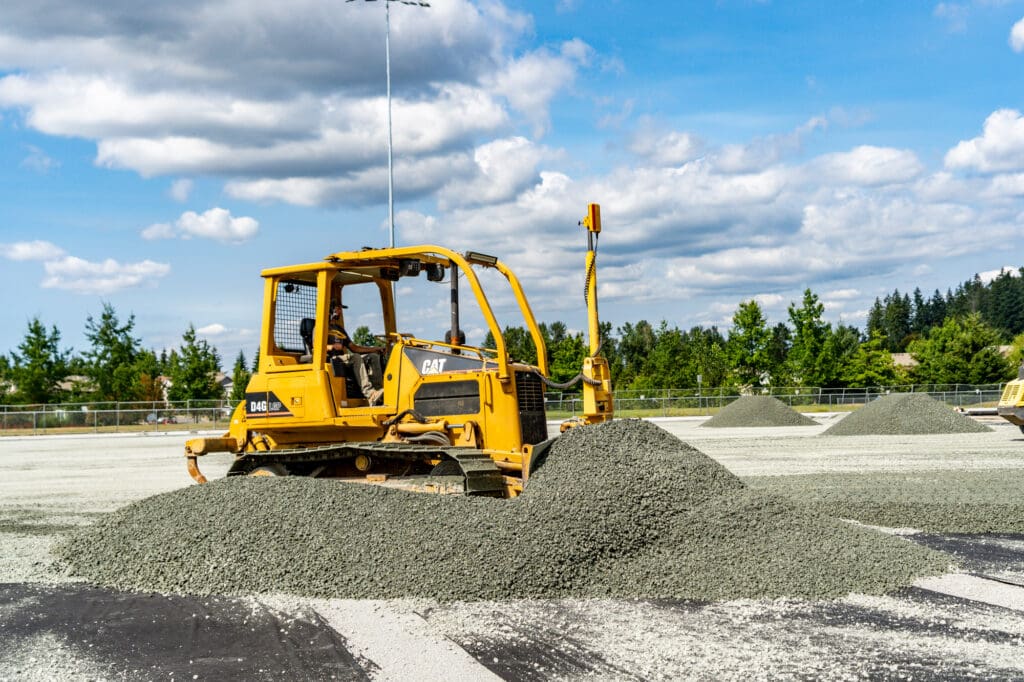 A bulldozer pushes a pile of gravel forward.